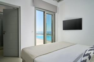 a white bedroom with a bed and a television at Villa j-view in Psarou