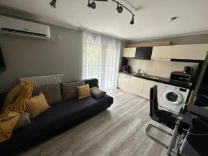 a living room with a black couch and a kitchen at Dorina Wellness Apartman in Siófok