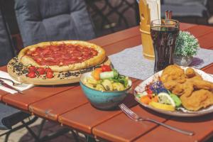 einen Tisch mit zwei Tellern Essen und einer Pizza in der Unterkunft Hotel Styrolerhof in Steeg