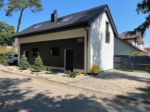 a small white building with a door on a street at Apartamenty przy Parku -150m od plaży in Darłówko