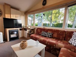 een woonkamer met een bank en een tv bij Chalet E009 with a large garden in Renswoude