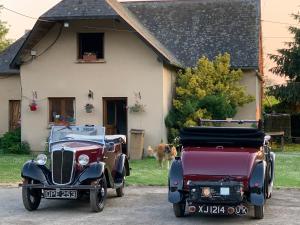 two old cars and a dog in front of a house at logement dans ferme equestre in Lyons-la-Forêt