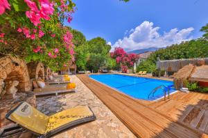 uma piscina exterior com um deque, cadeiras e flores em La Salvia Hotel Kas em Kas