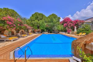 einen großen Pool mit Stühlen und Bäumen in der Unterkunft La Salvia Hotel Kas in Kaş