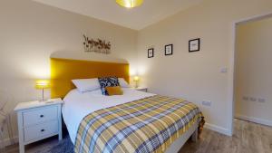 a bedroom with a bed with a yellow headboard at Primera Barn in Witney