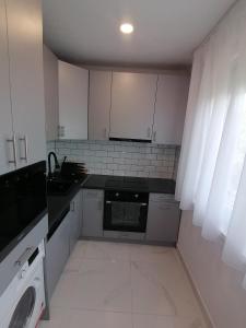 a small kitchen with white cabinets and a dishwasher at Borsalino Apartman in Veszprém