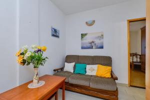 ein Wohnzimmer mit einem Sofa und einem Tisch mit Blumen in der Unterkunft Apartments Marija in Mali Lošinj