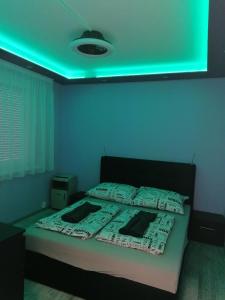 a bedroom with a bed with a green light at Borsalino Apartman in Veszprém