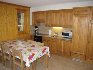 una cocina con armarios de madera y una mesa con mantel. en Residenz Plein Ciel, Wohnung CAPRICORNE VEYS240 en Veysonnaz