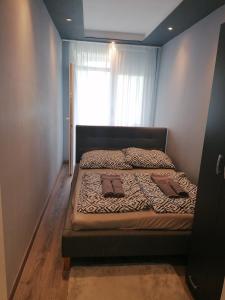 a bed in a small room with a window at Borsalino Apartman in Veszprém