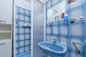 ein blaues Badezimmer mit einem Waschbecken und einem Spiegel in der Unterkunft Apartments Marija in Mali Lošinj