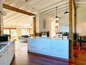 a large kitchen with white cabinets and a living room at Allusion Farmstay Cellar House Heated Pool - Fire Pit - Pizza Oven - Pool Table - Sleeps 16 in Yankalilla