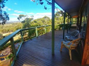 a porch with two chairs and a view of the wilderness at Allusion Farmstay Cellar House Heated Pool - Fire Pit - Pizza Oven - Pool Table - Sleeps 16 in Yankalilla