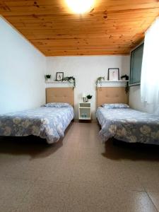 two beds in a room with a wooden ceiling at B&B and Apartments El Charco Azul in El Risco