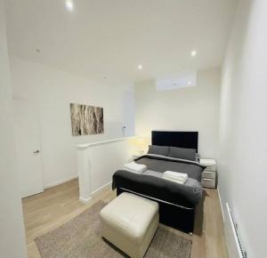 sala de estar con sofá negro y taburete en Spacious Flat, Fast WiFi, Free Parking, en Londres