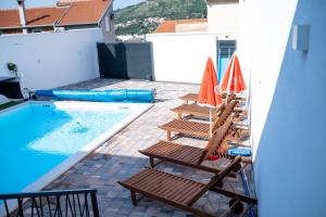 two lounge chairs and umbrellas next to a swimming pool at Villa UpTown in Mostar