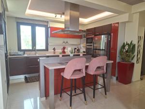 Villa Maria في شاراكي: مطبخ مع كراسي وردية في جزيرة المطبخ