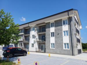 a building with a car parked in a parking lot at Apartman Silver Lux Srebrno jezero in Veliko Gradište
