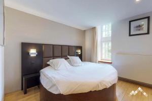 1 dormitorio con 1 cama grande con sábanas blancas en Dépendance du châteaux de Modave, en Modave
