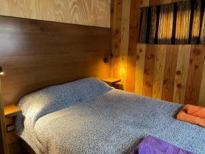 1 dormitorio con 1 cama con pared de madera en Cabaña de Montaña en San Martín de los Andes