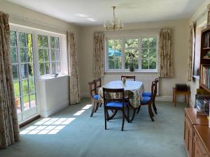 a dining room with a table and chairs and windows at Rectory Bungalow Holiday Apartment in Lower Brailes