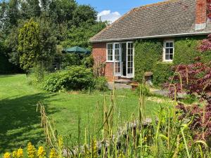 a house with a garden and an umbrella at Rectory Bungalow Holiday Apartment in Lower Brailes