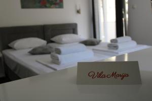 ein Bett mit weißen Kissen und ein Schild auf dem Tisch in der Unterkunft Villa Marija in Trebinje
