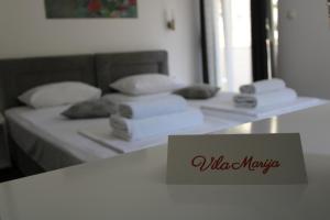 a bed with white pillows and a sign on a table at Villa Marija in Trebinje