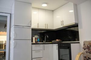  La cuisine est équipée de placards blancs et d'un réfrigérateur. dans l'établissement Villa UpTown, à Mostar