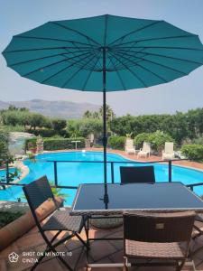 a table with an umbrella next to a swimming pool at Casolare Giummari in Carini