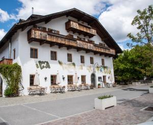 a large white building with a wooden roof at Landhotel Gasthof Zum Löwen in Rodengo
