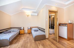 two beds in a room with a kitchen and a bathroom at Willa Dorotka in Dąbki