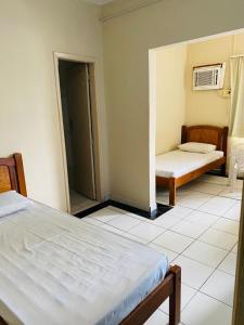 Habitación con 2 camas y puerta a un dormitorio en Hotel Cristal, en Rondonópolis