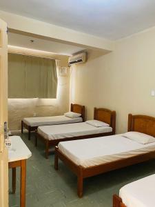 Un grupo de 4 camas en una habitación en Hotel Cristal, en Rondonópolis