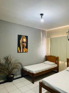 una camera con due letti e una pianta di Hotel Cristal a Rondonópolis