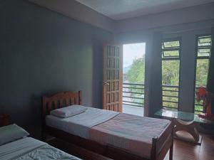 a bedroom with two beds and a large window at Banaue Pink Eco hostel in Banaue