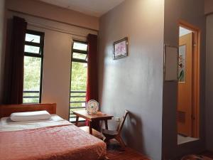 a bedroom with a bed and a table and a window at Banaue Pink Eco hostel in Banaue
