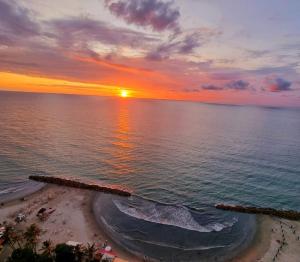 um pôr-do-sol sobre o oceano com uma praia de areia em Apartamentos Palmetto - Frente al Mar em Cartagena de Indias
