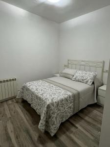 1 dormitorio blanco con 1 cama y suelo de madera en CASA 1860 CANDELEDA, en Candeleda