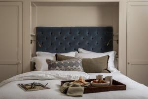 a bed with a blue headboard and a tray of food on it at No 5 Winchester in Winchester