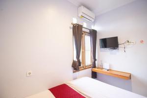 a bedroom with a bed and a tv and a window at Halona Residence near Pakuwon Mall Jogja Mitra RedDoorz in Yogyakarta