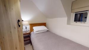 a small bedroom with a bed and a window at Bushnells Cottage in Oxford