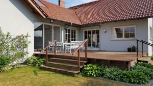 ein Haus mit einer Holzterrasse mit zwei Stühlen darauf in der Unterkunft Błękitny Domek in Wydminy