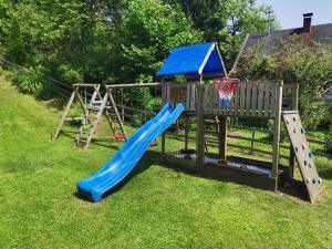 einen Spielplatz mit einer blauen Rutsche und einem Basketballkorb in der Unterkunft Lendorfer Cottage in Feldkirchen in Kärnten