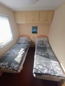 2 camas en una habitación pequeña con ventana en Mobilní dům u Mikeše Trhové Sviny - Rejta, en Trhové Sviny