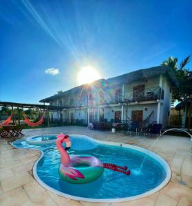 a swimming pool with a pink flamingo in the water at Pousada Ventos do Norte in Barra Grande