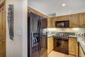 a kitchen with wooden cabinets and a stainless steel refrigerator at 1BR Plus Den, Heart of Beaver Creek Village in Beaver Creek