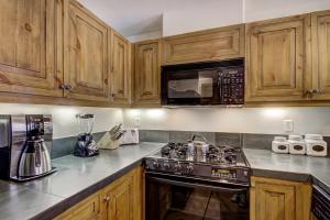 a kitchen with a stove and a microwave at 1BR Plus Den, Heart of Beaver Creek Village in Beaver Creek