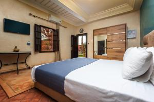 a bedroom with a large bed and a television at Villa Gardens Diafa in Marrakesh