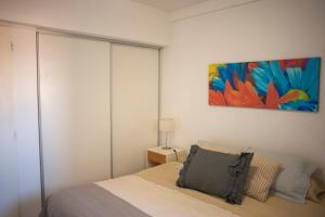 1 dormitorio con 1 cama y una pintura en la pared en Departamento Premium con cochera y piscina en Bahía Blanca